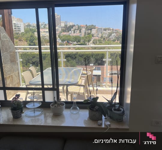 חלון הזזה מאלומיניום כהה עם רשת נגד חרקים המשקיף למרפסת